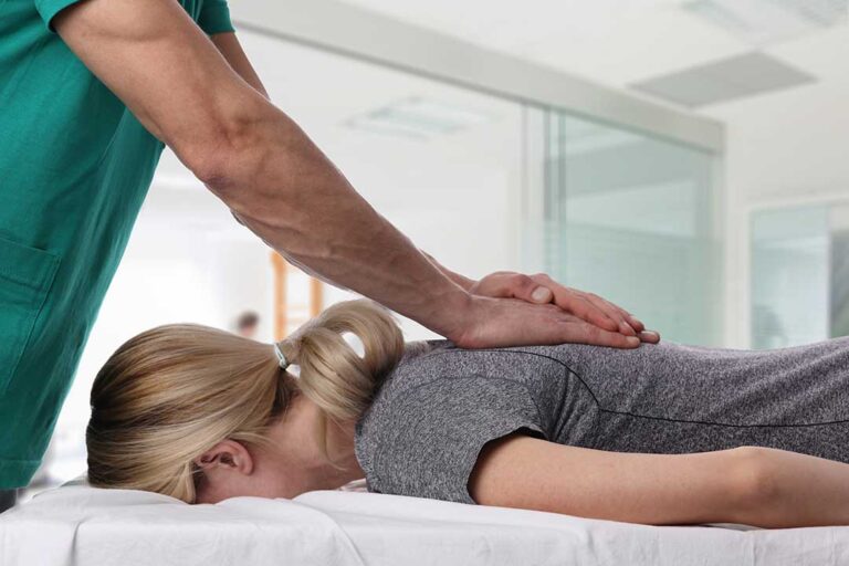 A chiropractor demonstrating a gentle spinal adjustment to a patient lying on a padded table.