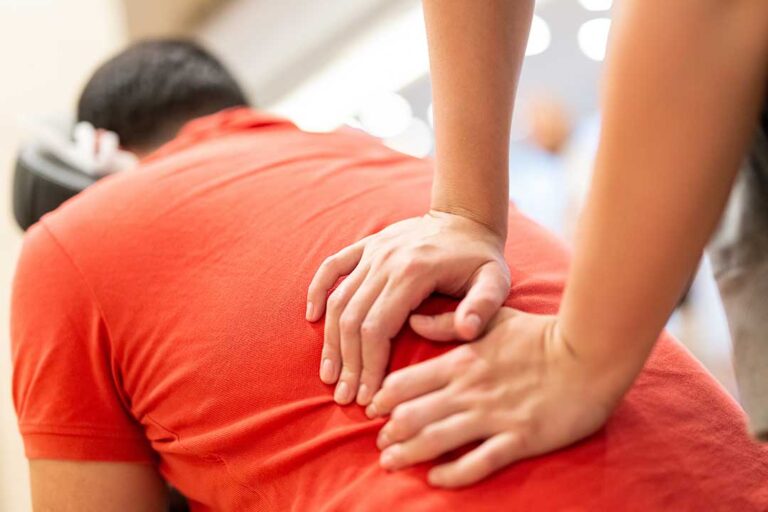 Pregnant woman lying on her side with pillows while receiving a gentle back assessment